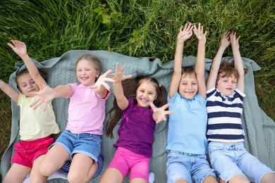 Photo of Happy children lying on blanket in nature, top view