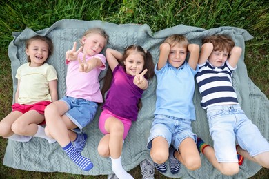 Photo of Happy children lying on blanket in nature, top view