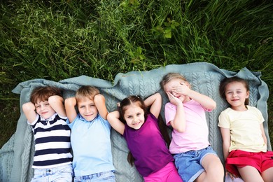 Photo of Happy children lying on blanket in nature, top view