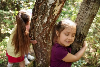 Photo of Cute little girls near trees in nature, selective focus