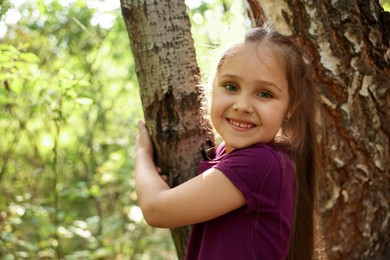 Photo of Cute little girl near tree in nature