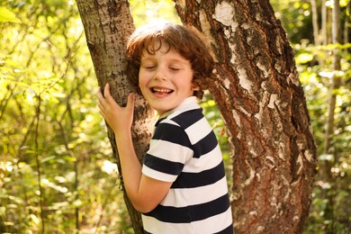 Photo of Cute little boy near tree in nature