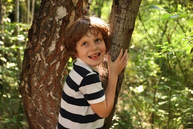 Photo of Cute little boy near tree in nature