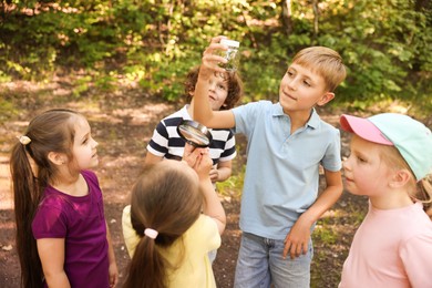 Photo of Children with jar and magnifying glass in nature
