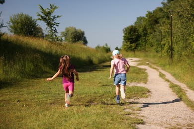Photo of Cute little girls running in nature, back view