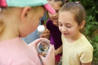 Photo of Children with jar of snails in nature, closeup