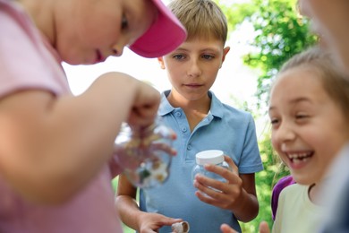 Photo of Children with jars of snails in nature, closeup