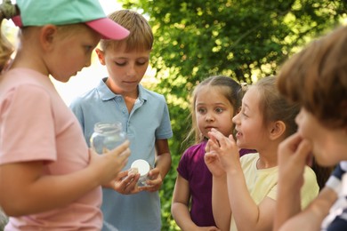 Photo of Children with snail and jars in nature, selective focus
