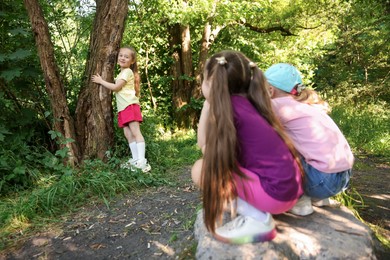 Photo of Cute little girl near tree and her friends in nature, selective focus
