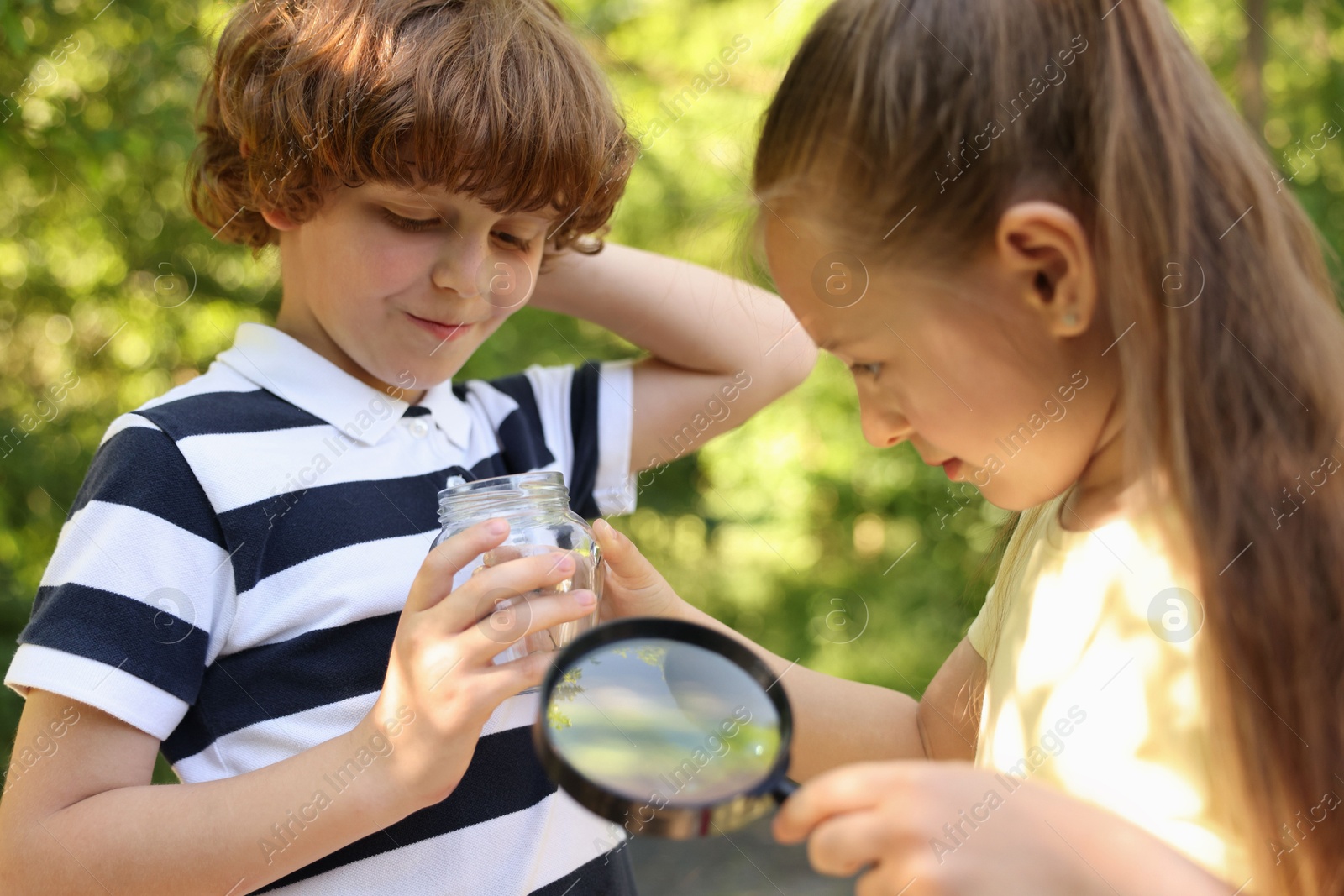 Children with magnifying glass and jar in nature Photo of Children with magnifying glass and jar in nature