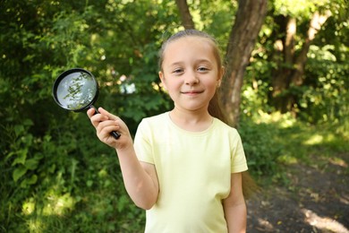 Photo of Cute little girl with magnifying glass in nature
