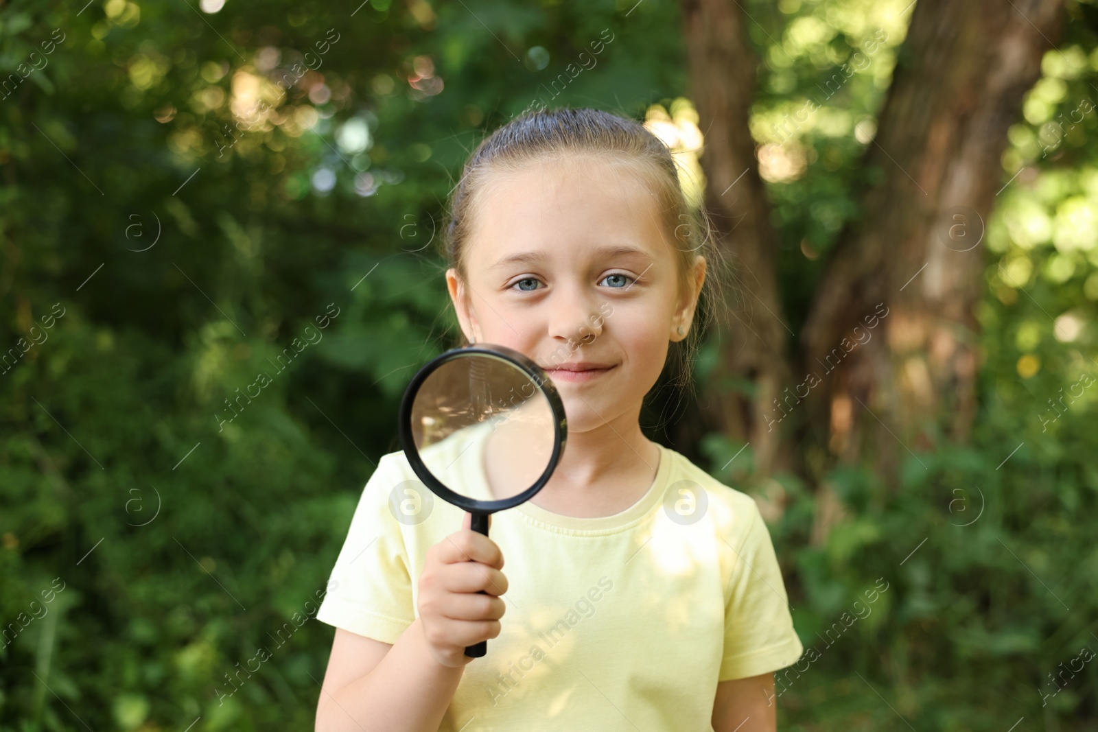 Photo of Cute little girl with magnifying glass in nature