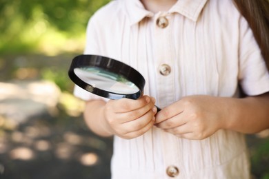 Photo of Little girl looking through magnifying glass in nature, closeup