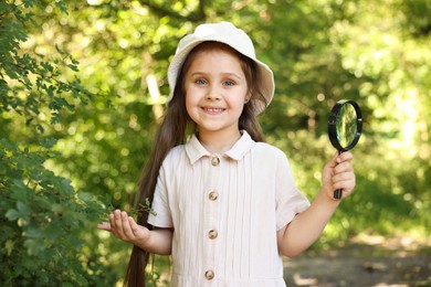 Photo of Cute little girl with magnifying glass in nature