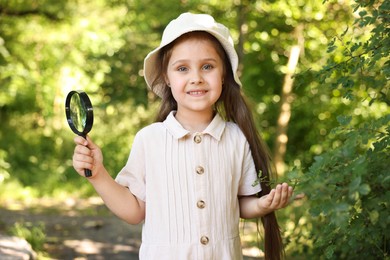 Photo of Cute little girl with magnifying glass in nature
