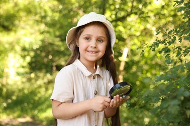Photo of Cute little girl with magnifying glass in nature