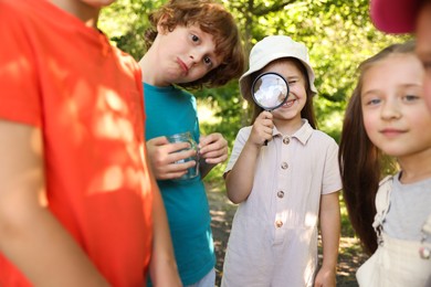 Photo of Children with magnifying glass and jar in nature