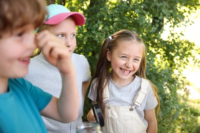 Photo of Children with magnifying glass in nature, selective focus