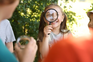 Photo of Group of children with magnifying glass in nature, selective focus