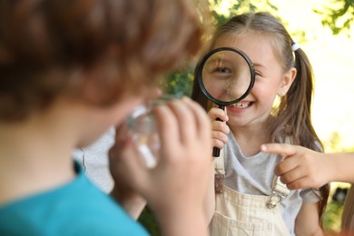 Photo of Group of children with magnifying glass in nature, selective focus
