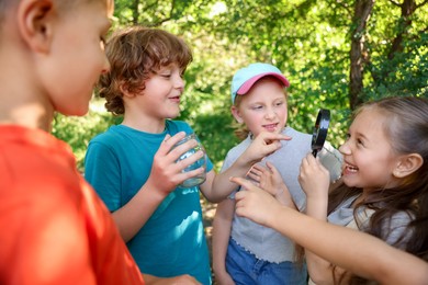 Photo of Children with magnifying glass and jar in nature