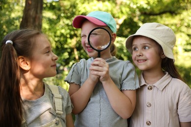 Photo of Children in nature. Cute little girl looking through magnifying glass outdoors