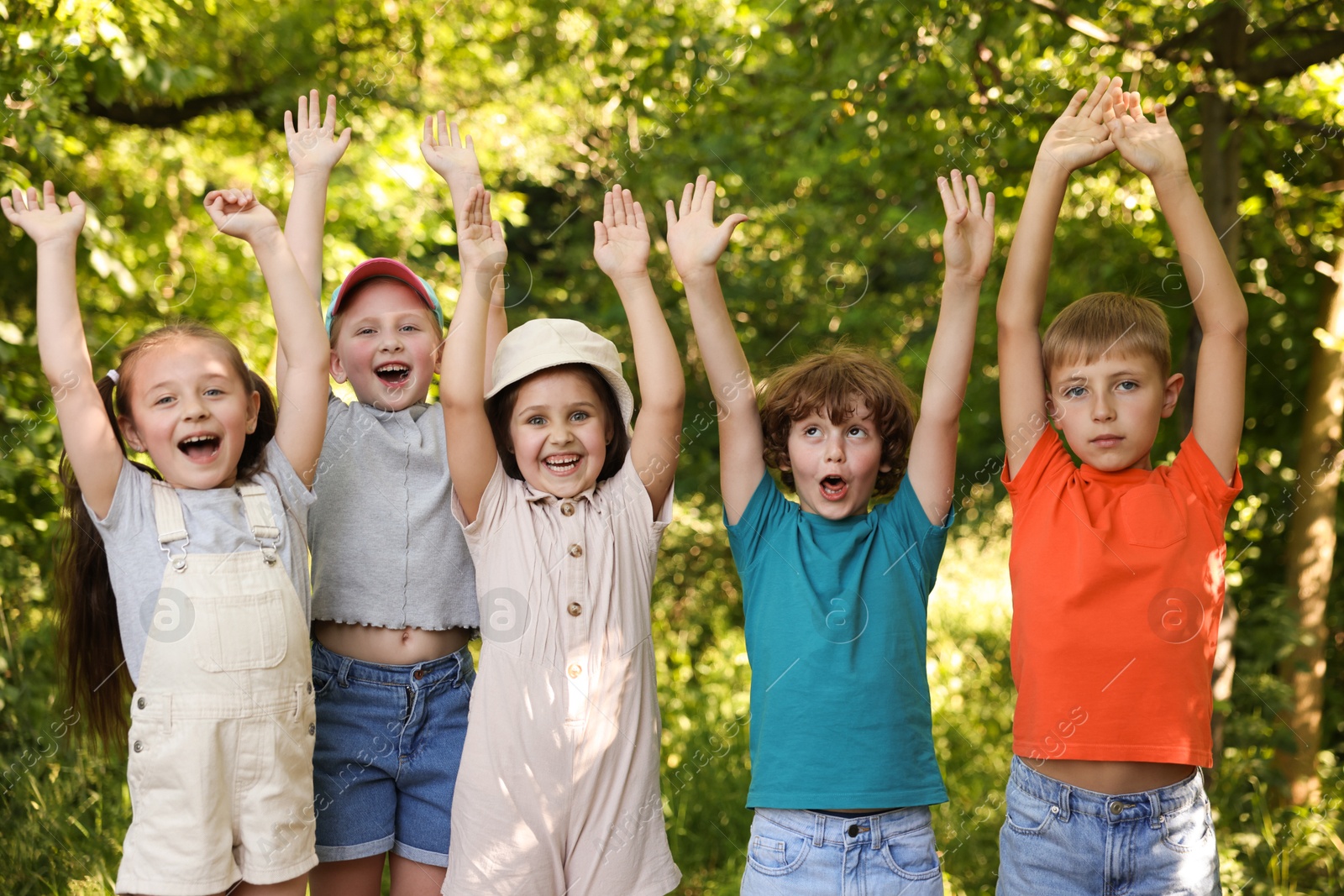 Happy children with raised hands in nature Photo of Happy children with raised hands in nature