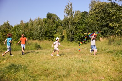 Photo of Children with colorful kite running in nature
