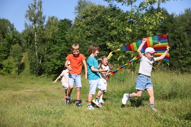 Photo of Children with colorful kite running in nature
