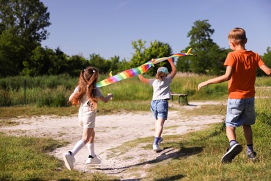 Photo of Children with colorful kite running in nature