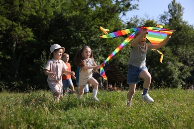 Photo of Children with colorful kite running in nature