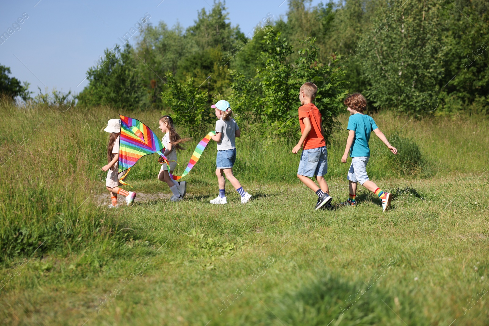 Children with colorful kite running in nature Photo of Children with colorful kite running in nature