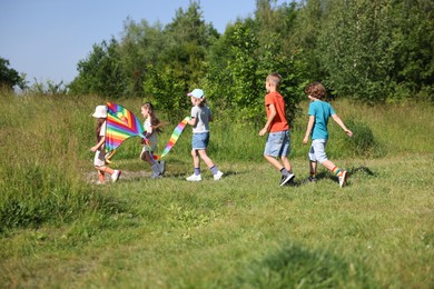 Photo of Children with colorful kite running in nature