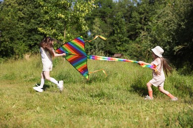 Photo of Cute little girls with colorful kite running in nature