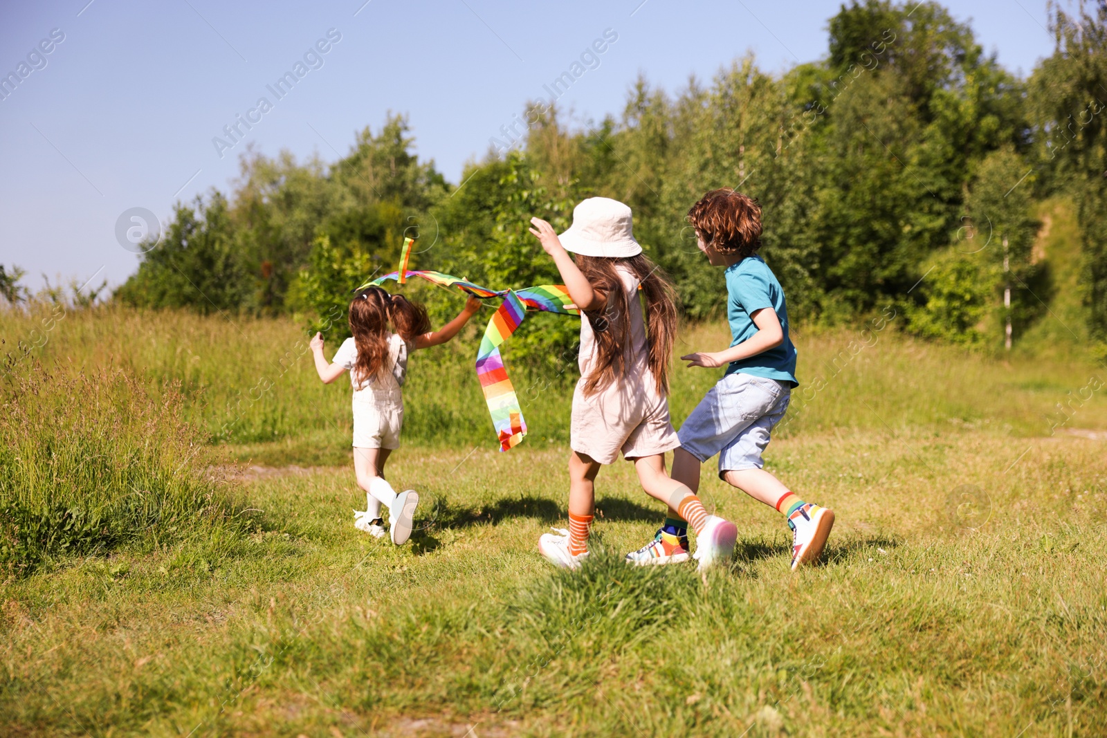 Children with colorful kite running in nature Photo of Children with colorful kite running in nature