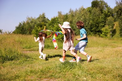 Photo of Children with colorful kite running in nature
