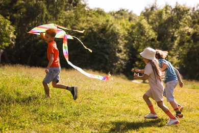 Photo of Children with colorful kite running in nature