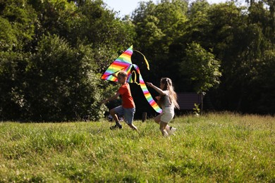 Photo of Children with colorful kite running in nature