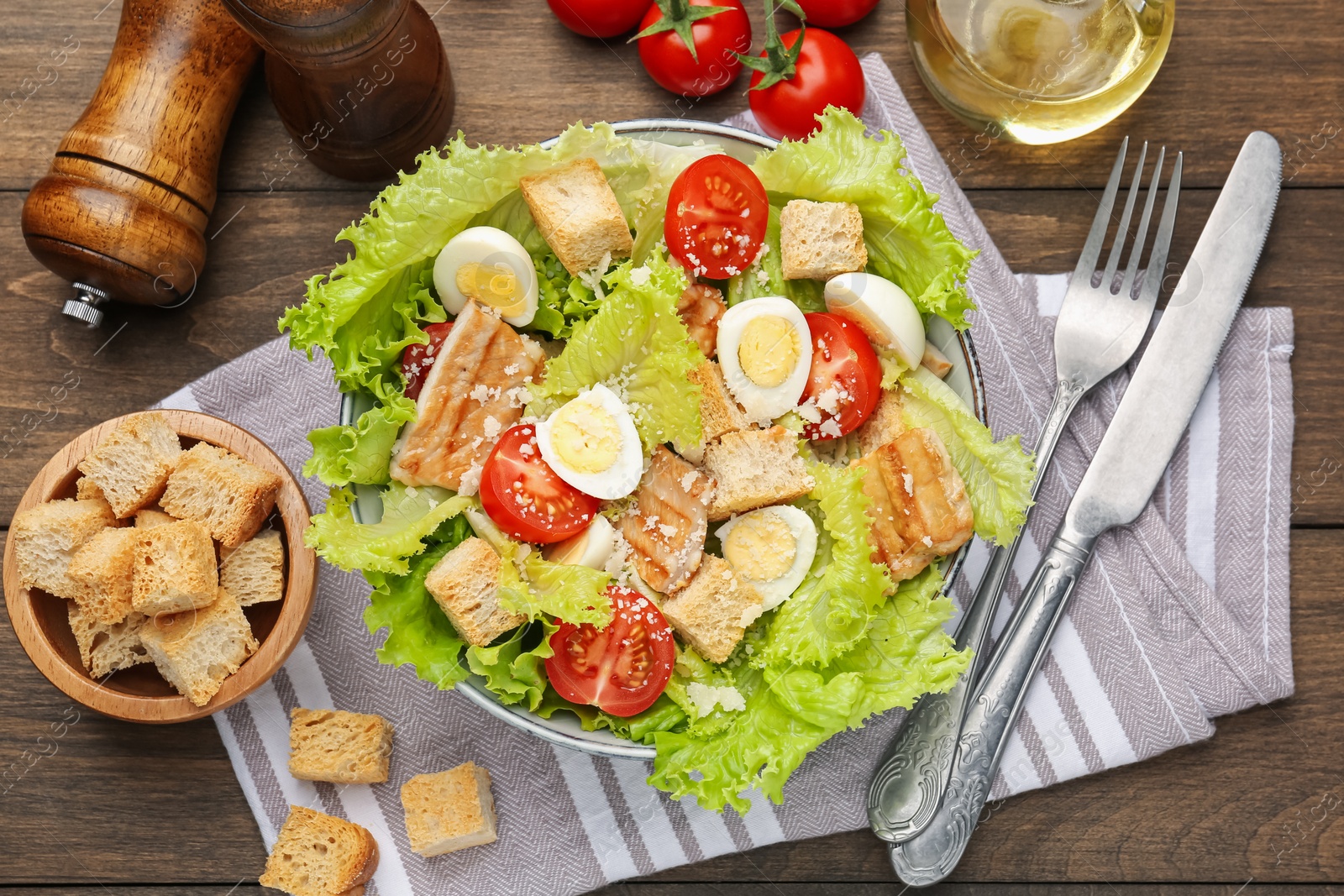 Photo of Delicious salad with croutons and ingredients on wooden table, flat lay