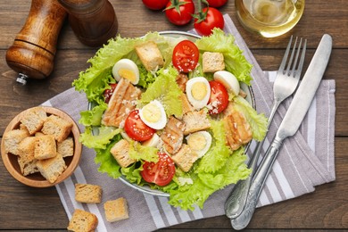 Photo of Delicious salad with croutons and ingredients on wooden table, flat lay