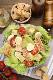 Photo of Delicious salad with croutons and ingredients on wooden table, flat lay