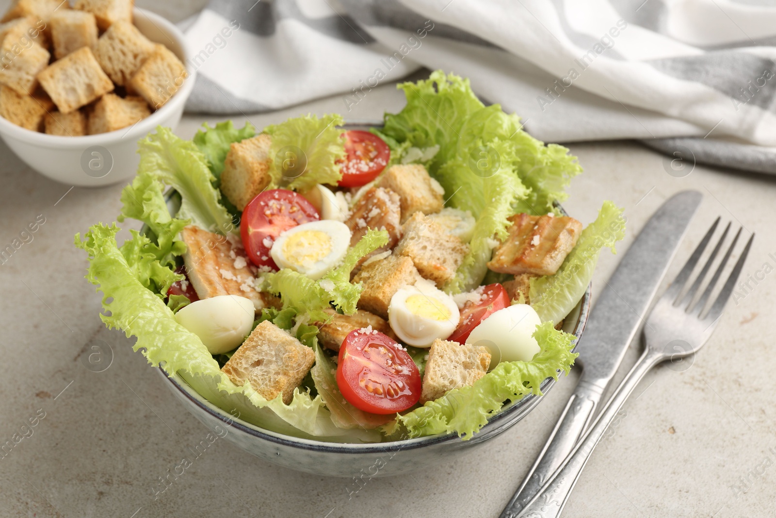 Photo of Delicious salad with croutons, chicken, quail eggs, tomato and cheese on grey table, closeup