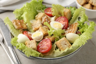 Photo of Delicious salad with croutons, chicken, quail eggs, tomato and cheese on grey table, closeup