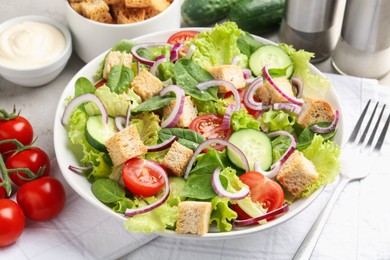 Photo of Delicious salad with croutons and vegetables served on light grey table, closeup