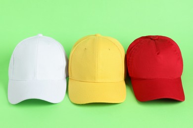 Photo of Colorful baseball hats on light green background