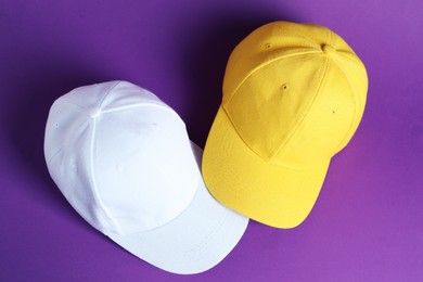 Photo of Baseball hats on violet background, top view