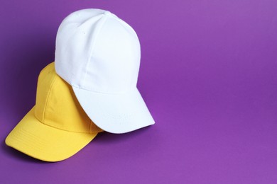 Photo of Baseball hats on violet background, space for text