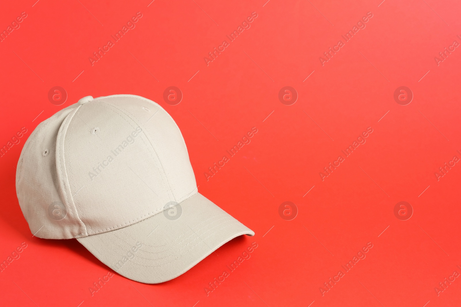 Beige baseball hat on coral background, space for text Photo of Beige baseball hat on coral background, space for text