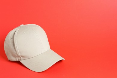 Photo of Beige baseball hat on coral background, space for text