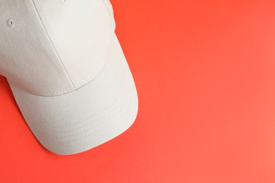 Photo of Beige baseball hat on coral background, top view. Space for text